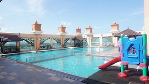A swimming pool with a slide, lounge chairs, and a view of the city. - Paya Bunga Hotel Terengganu (Kuala Terengganu)