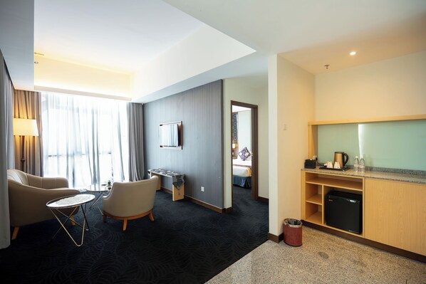 Habitación de hotel con sala de estar, kitchenette y vistas a la ciudad.