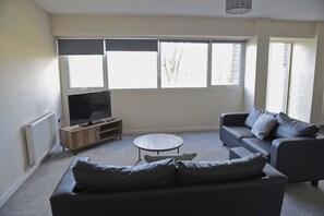 Relax in this spacious living room with a large window, flat-screen TV, and comfortable sofa.
