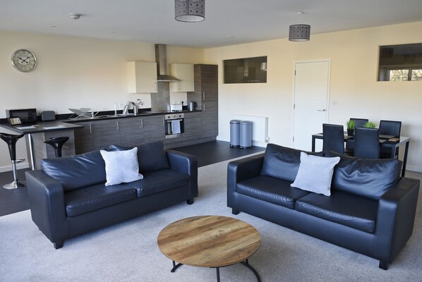 Relax in a spacious open-plan living area with two comfortable sofas and a modern kitchen.