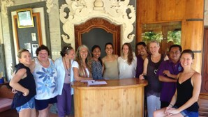Un grupo de personas de pie en un vestíbulo con un mostrador de recepción de madera y un arco decorativo.