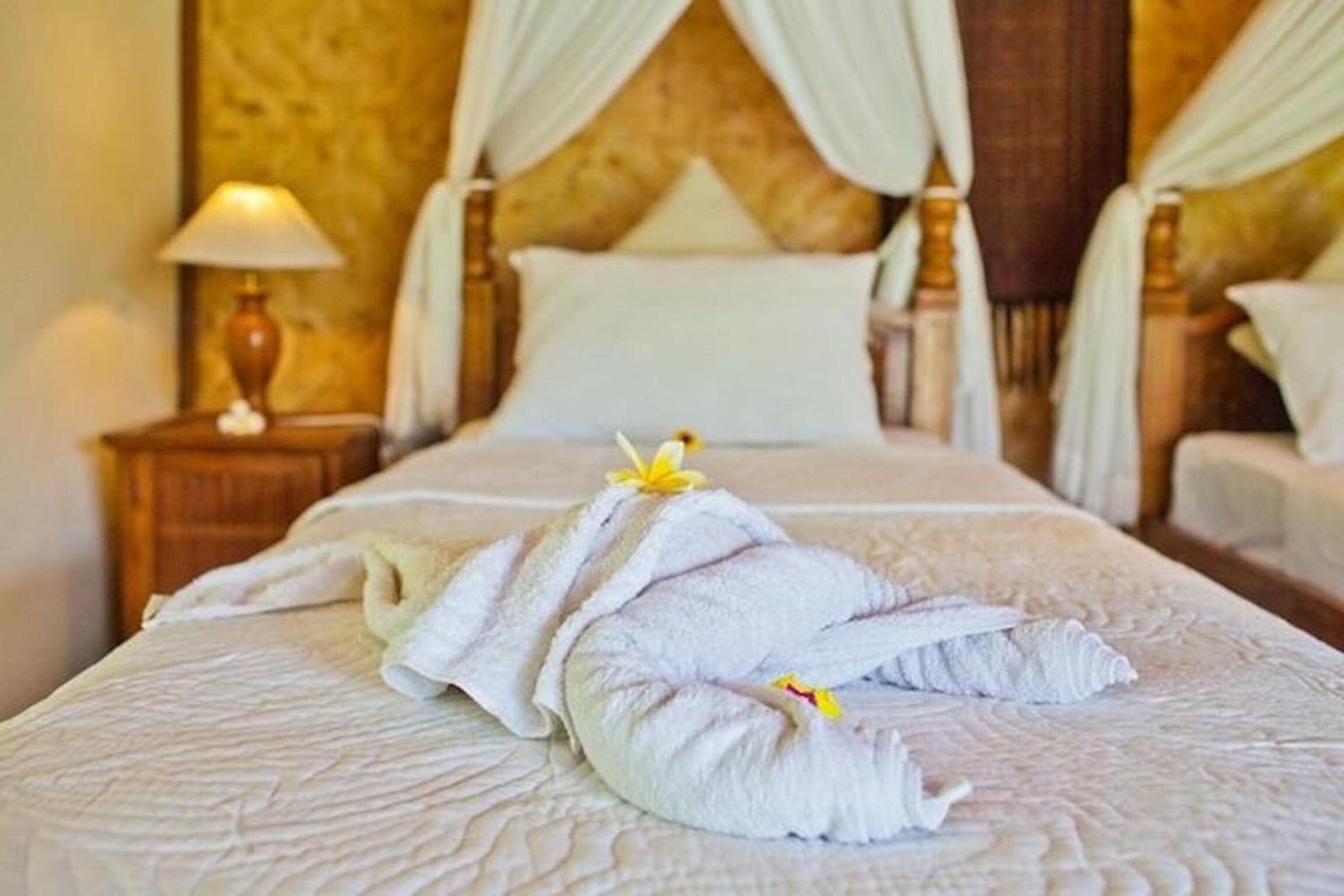 A hotel room with a bed, a nightstand with a lamp, and a headboard with curtains.