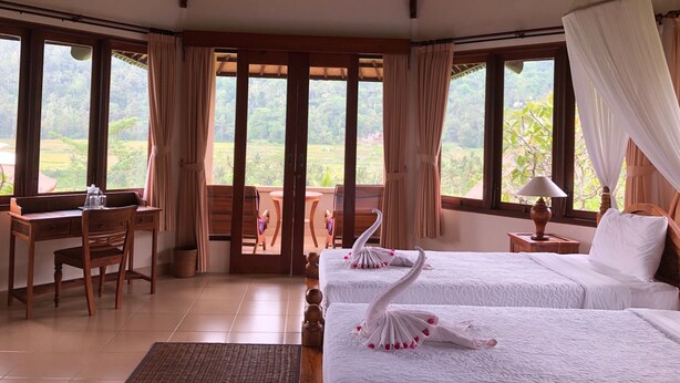 Una habitación con dos camas, un escritorio y vistas a un paisaje exuberante.