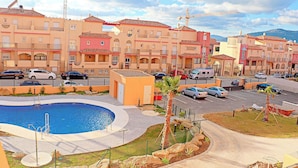 A residential area with a swimming pool, parked cars, and a construction crane in the background. - Apartment close to the beach (TARIFA)