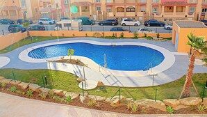 A swimming pool with a curved design, surrounded by a landscaped area with rocks and plants. - Apartment close to the beach (TARIFA)