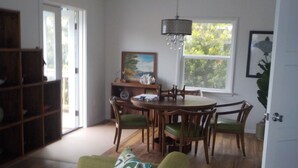 Een eetruimte met een ronde tafel en stoelen, een kroonluchter en een schilderij aan de muur.