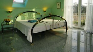 A bedroom with a skylight, a bed with a white bedspread, two bedside tables with lamps, and a view through a window.