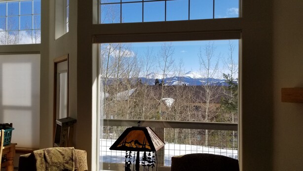 A room with a large window offering a view of mountains and trees. -    Enjoy the Summer Time in Views!  (Silverthorne)