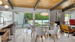 A modern kitchen with a glass island, stainless steel appliances, and a view of a swimming pool. - Mid-Century Modern Gem - Pool Spa Fire Pit w/ Stunning Views in Vista Las Palmas (Palm Springs)