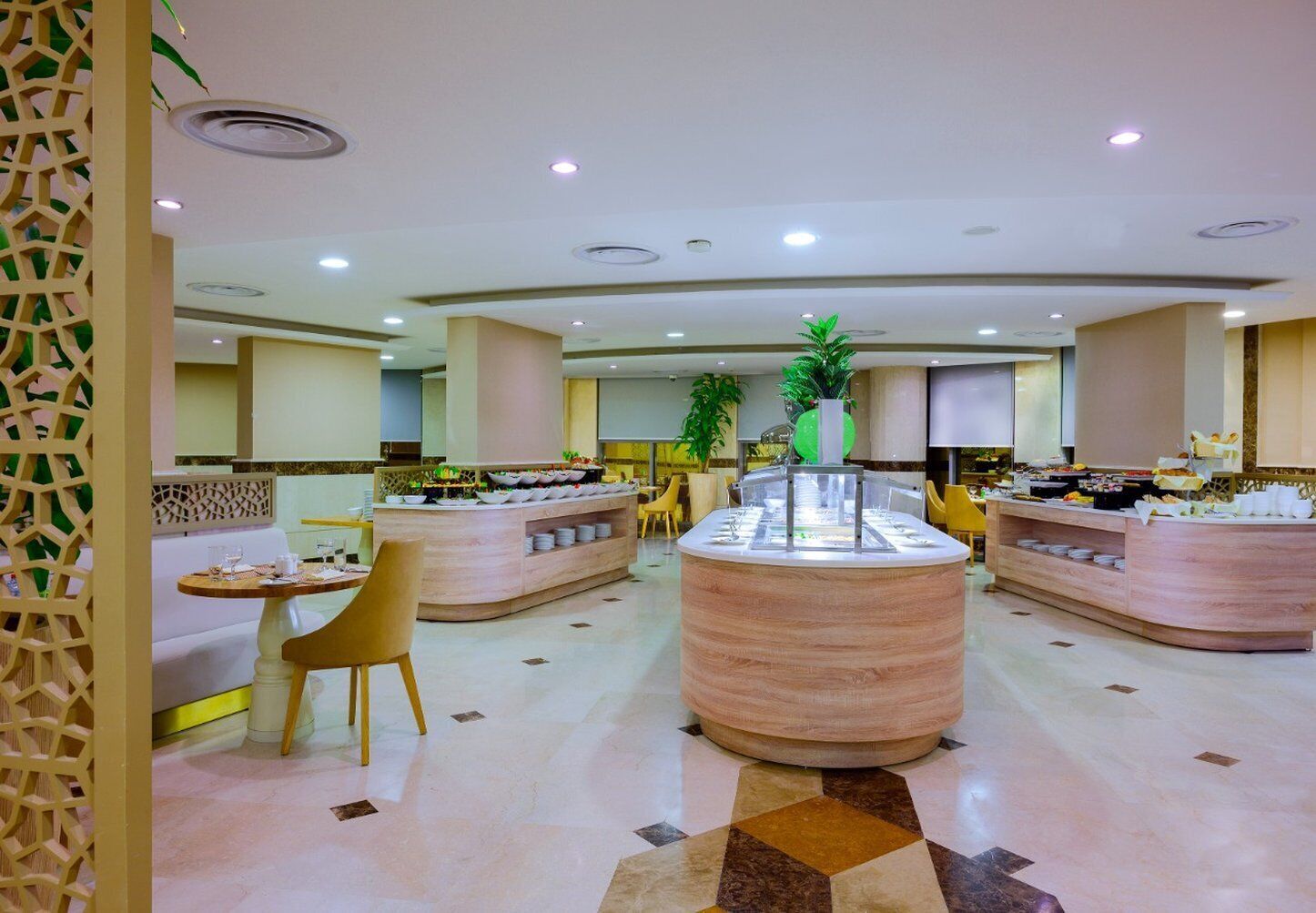 Un hall d’hôtel moderne avec un comptoir d’accueil central, des espaces de détente et un buffet.