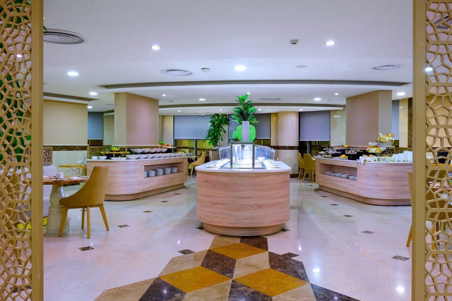 Un vestíbulo de hotel moderno con una recepción central, varias zonas de estar y un arreglo floral decorativo.
