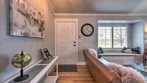 Een moderne woonkamer met een witte deur, een wereldbol op een plank, een klok aan de muur en een raam met uitzicht.