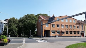 A multi-story building with a brick facade, a pedestrian crossing, and a street sign. - Rum i Centrum (Vetlanda)