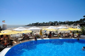 A pool area with umbrellas, lounge chairs, and a view of the beach and ocean. - Villa l'Olivier, Chambre d'Hôtes Les Volets Bleus (Vaux-sur-Mer)