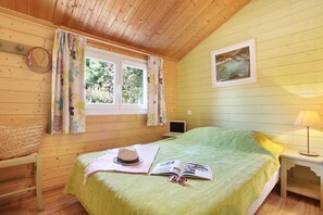A cozy room with a bed, a window with curtains, a lamp, and a painting on the wall.