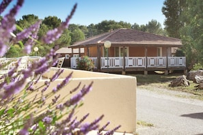 A building with a tiled roof, a balcony with white railings, and a gravel driveway.