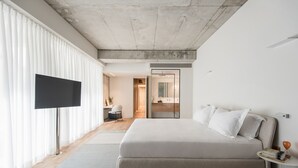 A modern bedroom with a large bed, a flat-screen TV, and a walk-in closet.