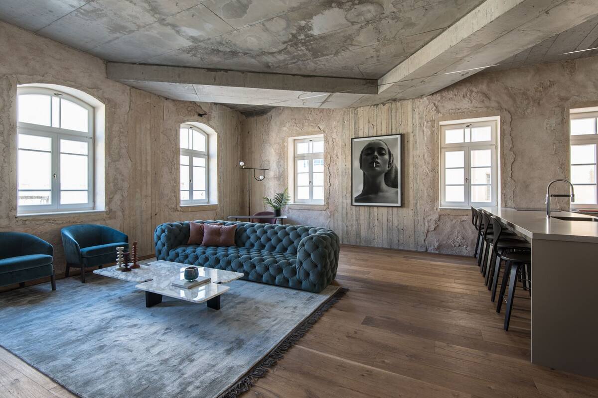 A spacious living area with a large blue sofa, a coffee table, and a bar area with stools.