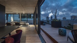A modern rooftop terrace with a dining area, seating, and a view of the city skyline.