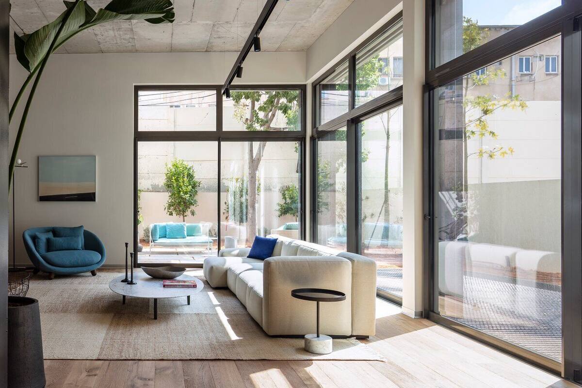 A modern living room with a sofa, a round coffee table, and a large window offering a view of the outdoors.