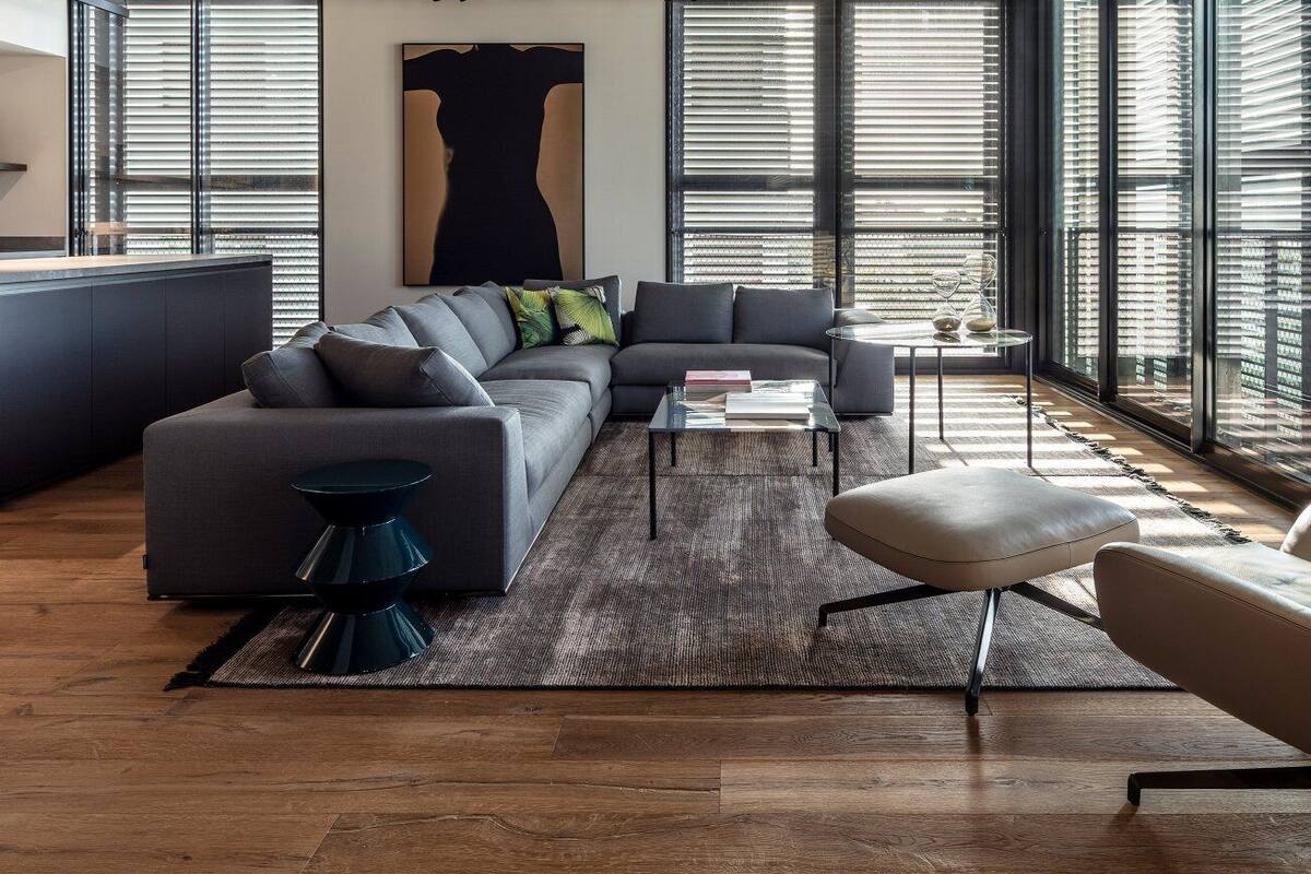 A modern living room with a sofa, armchair, coffee table, and a rug.