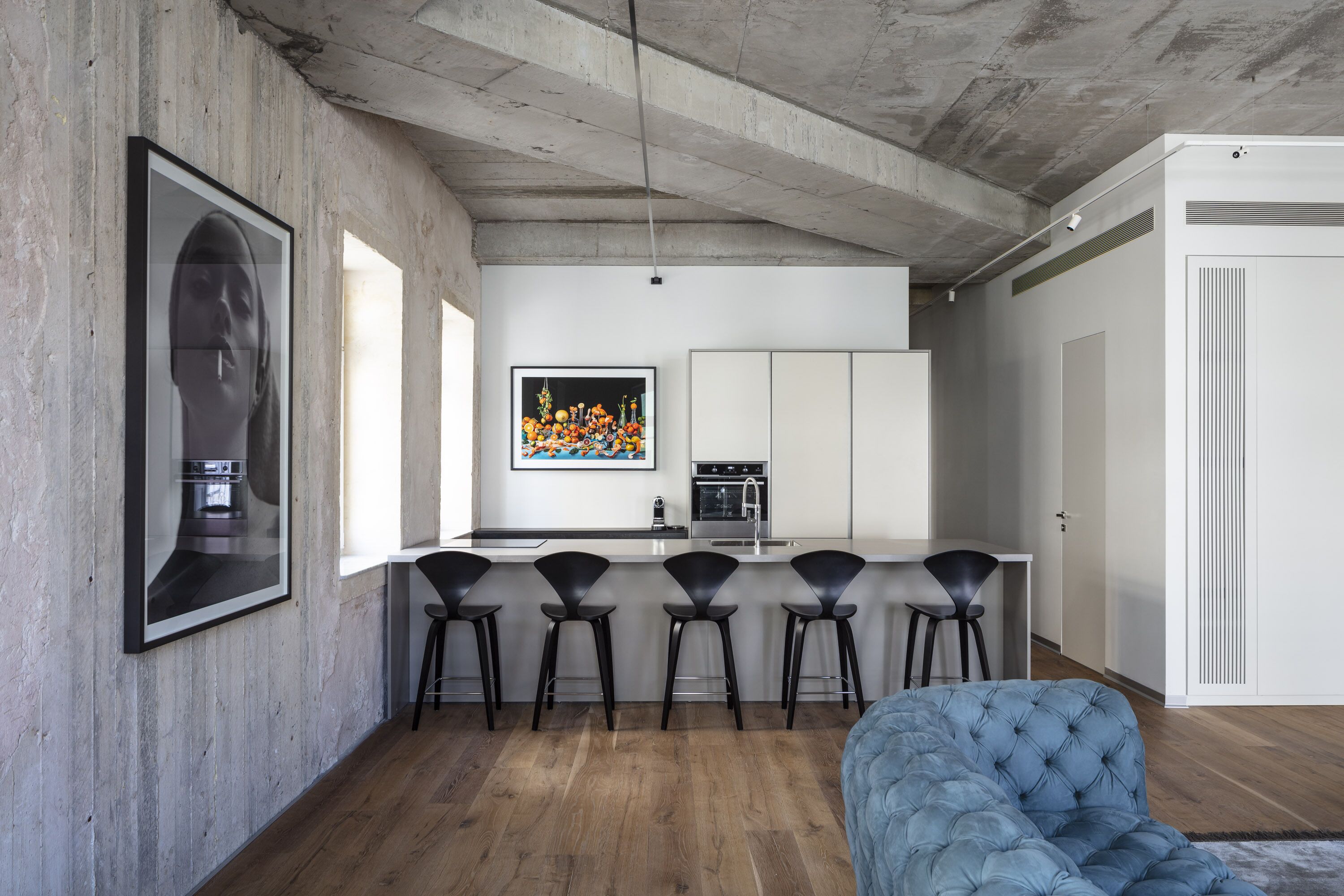A modern kitchen with a central island, bar stools, and a large framed artwork on the wall.