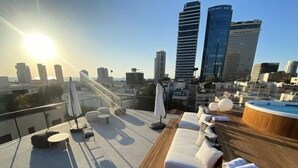 A rooftop terrace with lounge seating, a hot tub, and a city skyline view.