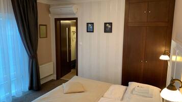 Hotelkamer met een bed, een kledingkast, een badkamer zichtbaar door een geopende deur en een wandlamp.