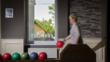 A bowling alley with a stone wall and a window with a view of greenery.