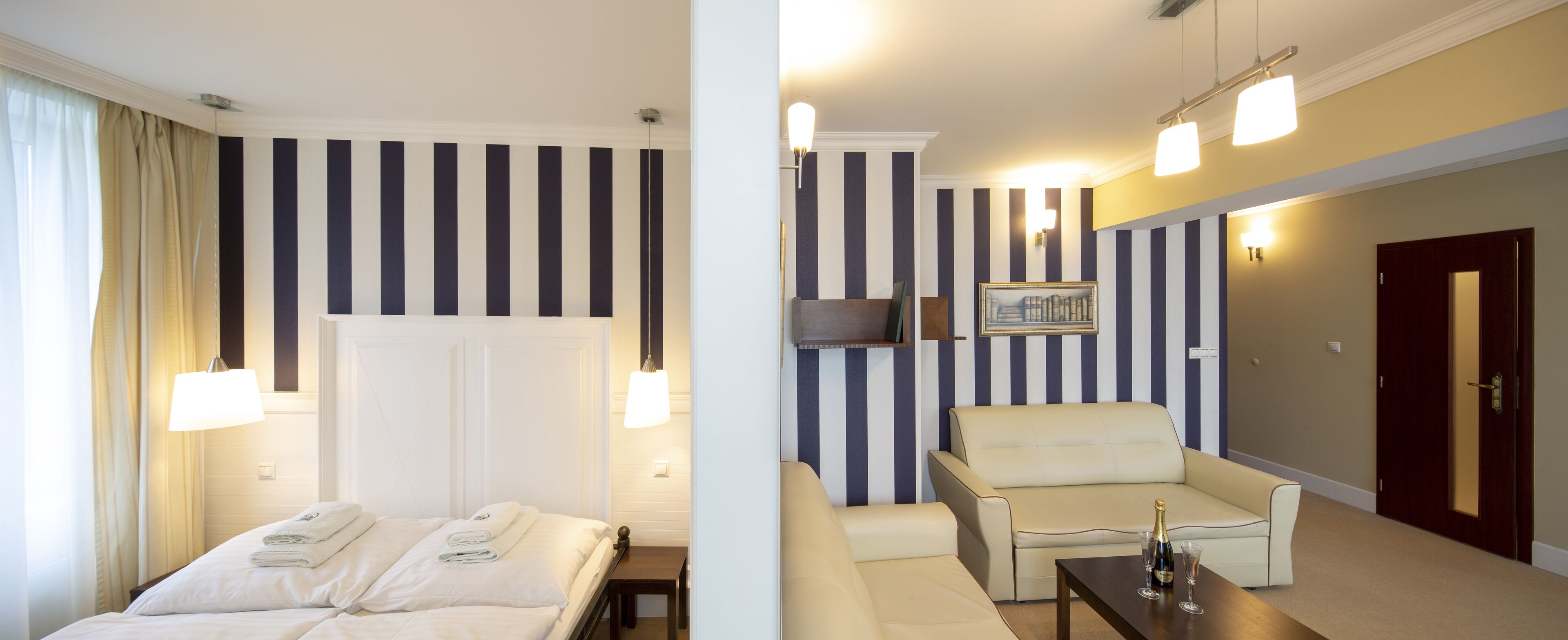 A hotel room with a bed, a chair, a small table, and a door.