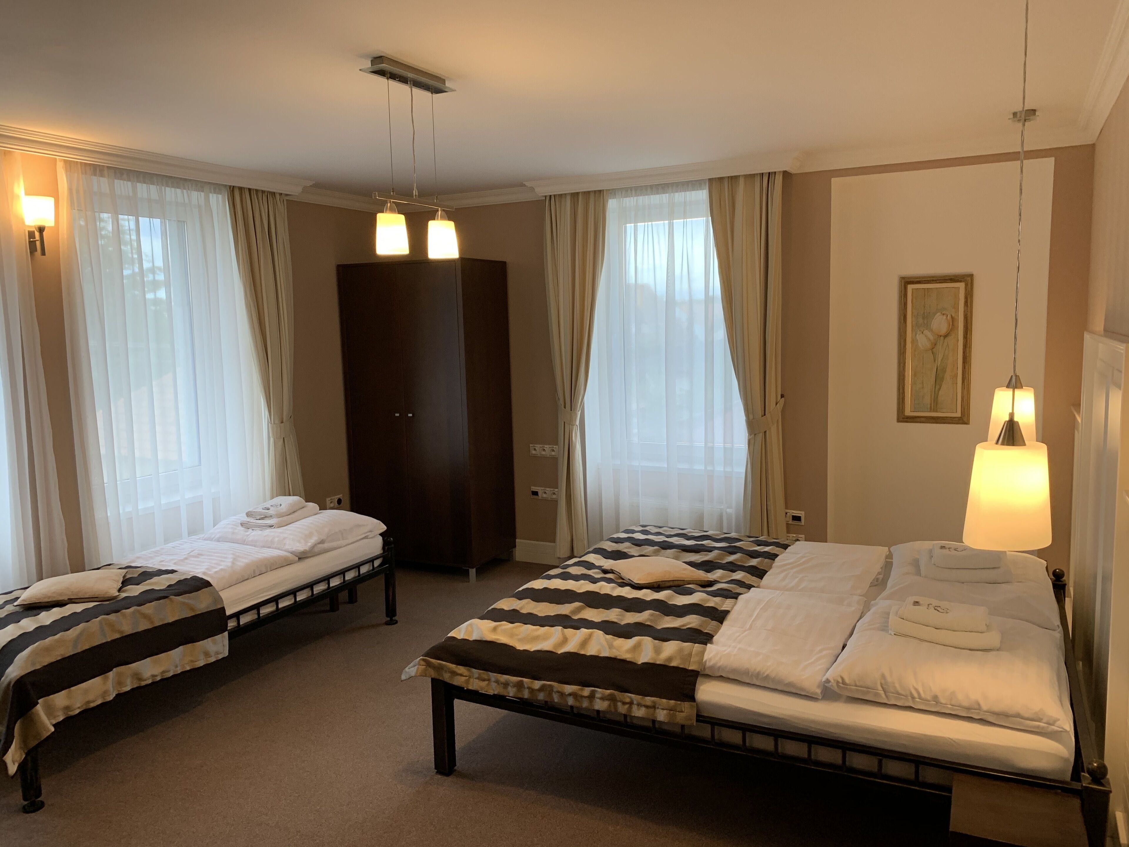 Ein Hotelzimmer mit zwei Betten, einem Kleiderschrank und einem Bild an der Wand.