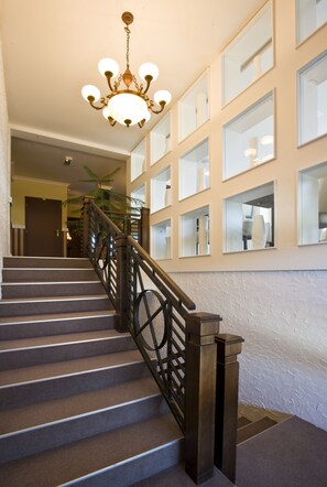 A staircase with a wooden handrail and a chandelier. - Pension Eden (Želiezovce)
