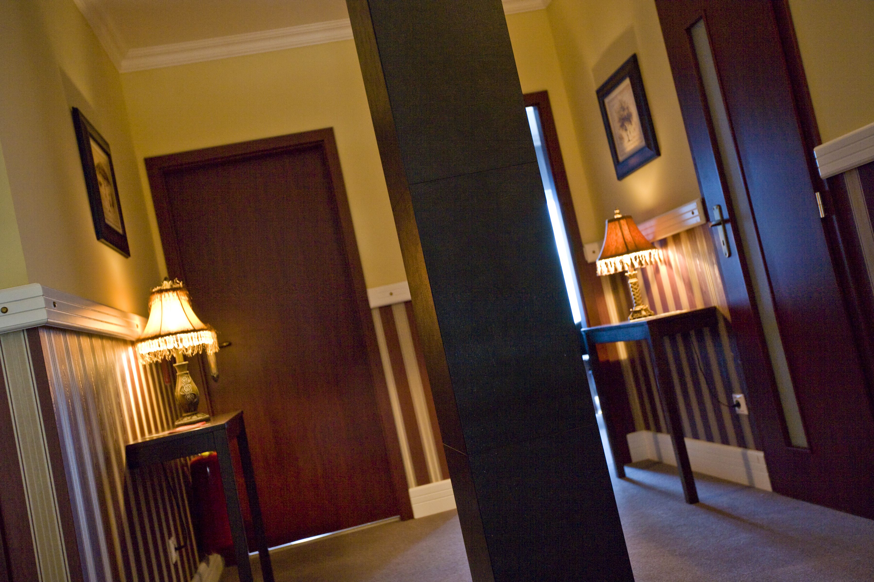 A hallway with a wooden door, a lamp, and a staircase.