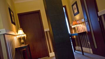 A hallway with a wooden door, a lamp, and a staircase.