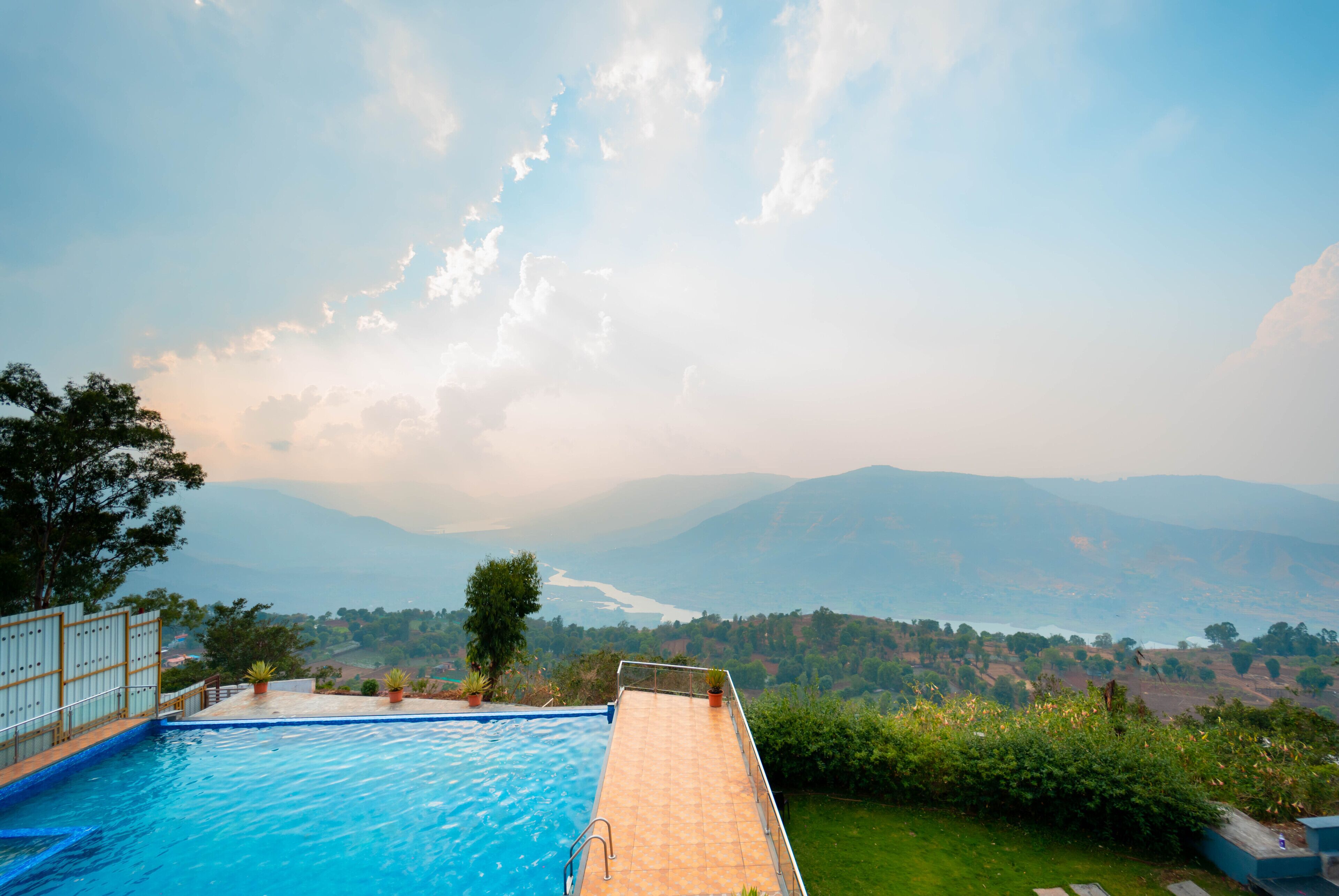Una piscina infinita con vistas a montañas y un río.