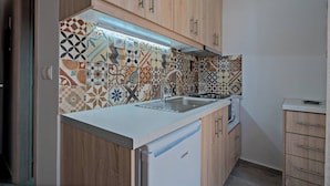 A kitchen with wooden cabinets, a white countertop, and a patterned backsplash. - Melina Apartment in the heart of Rethymno Old Town (Rethymno)