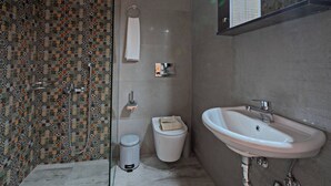 A bathroom with a patterned tile wall, a white toilet, a sink, and a trash can. - Melina Apartment in the heart of Rethymno Old Town (Rethymno)