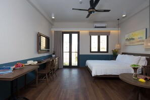 A hotel room with a bed, desk, chair, and a view of the outside.