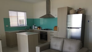 Una cocina moderna con una isla central, horno empotrado y refrigerador de acero inoxidable.
