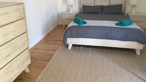 Un dormitorio con cama, dos mesitas de noche, un tocador y un aparador de madera.