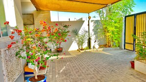 Un patio empedrado con plantas en macetas y un toldo amarillo.