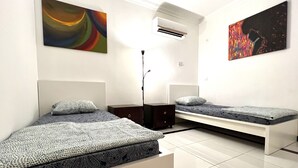Un dormitorio moderno con dos camas, una mesita de noche, un equipo de aire acondicionado y pinturas abstractas en las paredes.