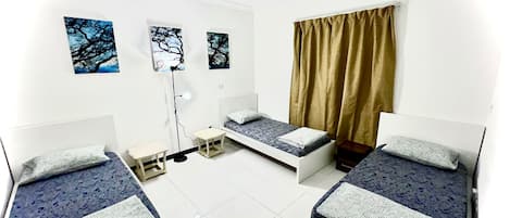 Una habitación con tres camas, un escritorio y una ventana con cortinas.