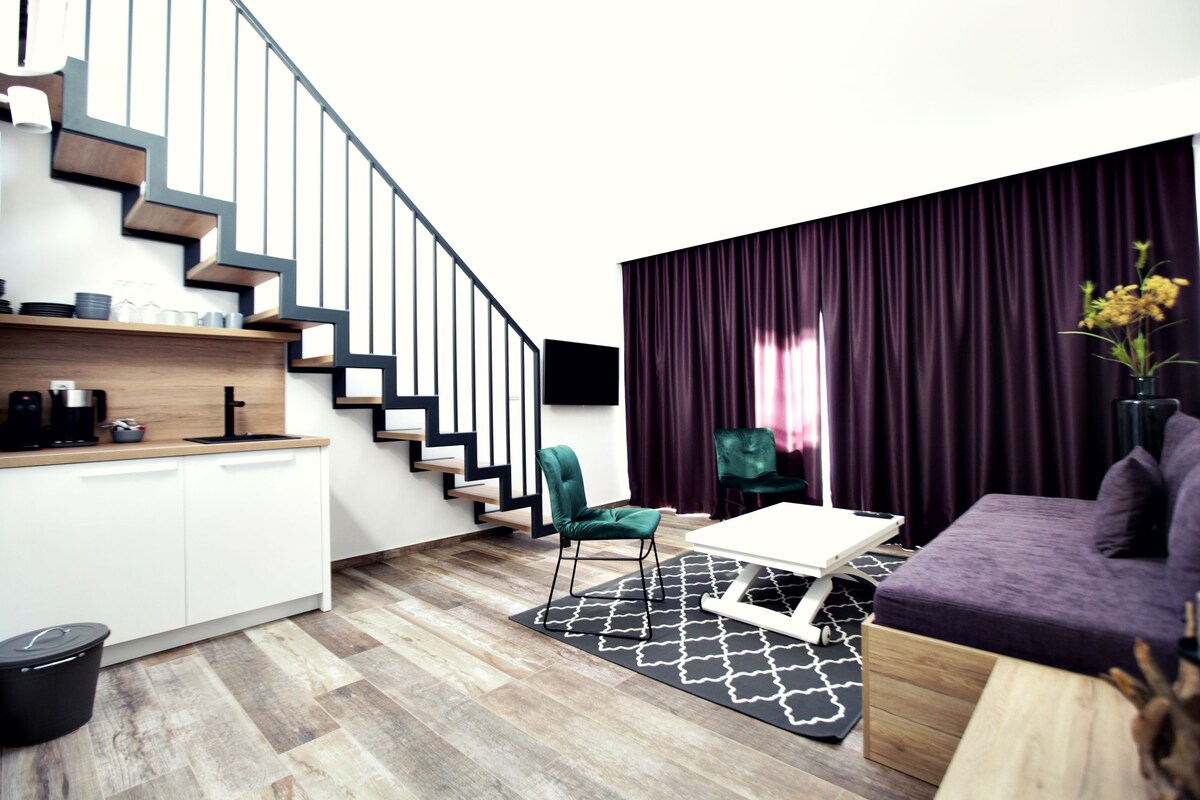 Un espace de vie moderne comprenant un escalier, un coin cuisine, une table à manger et un canapé.