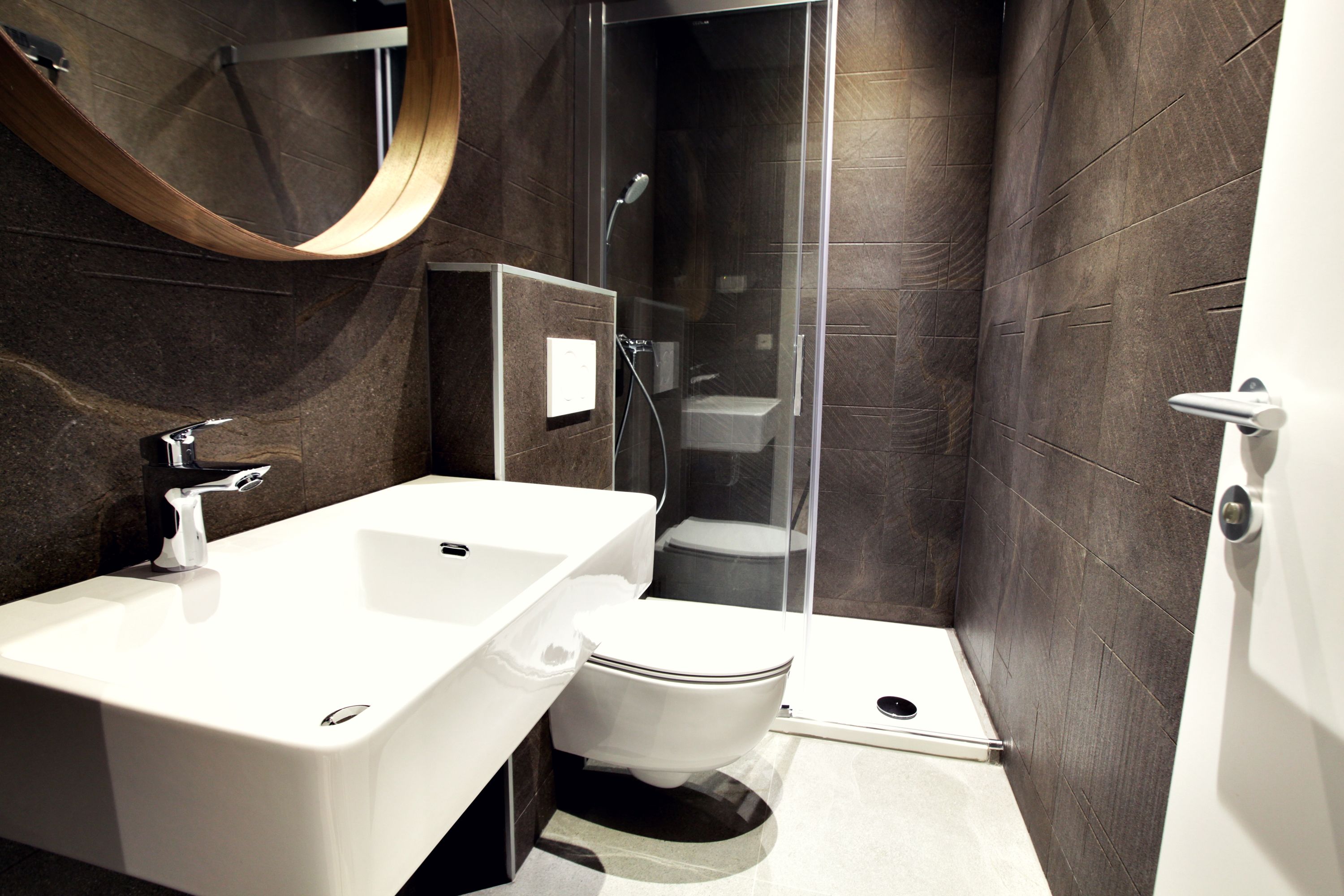 A modern bathroom with a white sink, toilet, and shower.