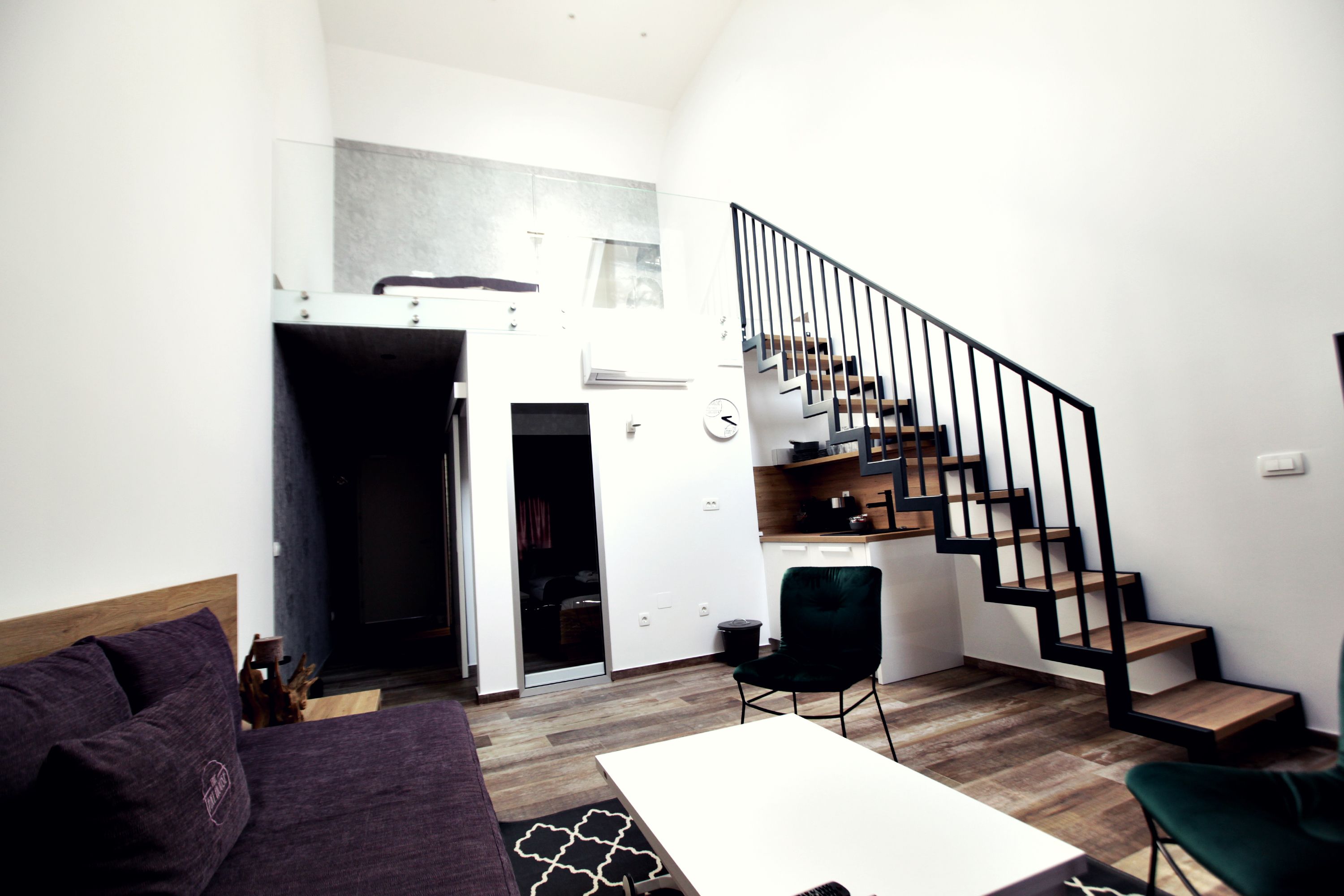 Un espacio habitable moderno con una escalera, un sofá, una mesa de comedor y una silla.