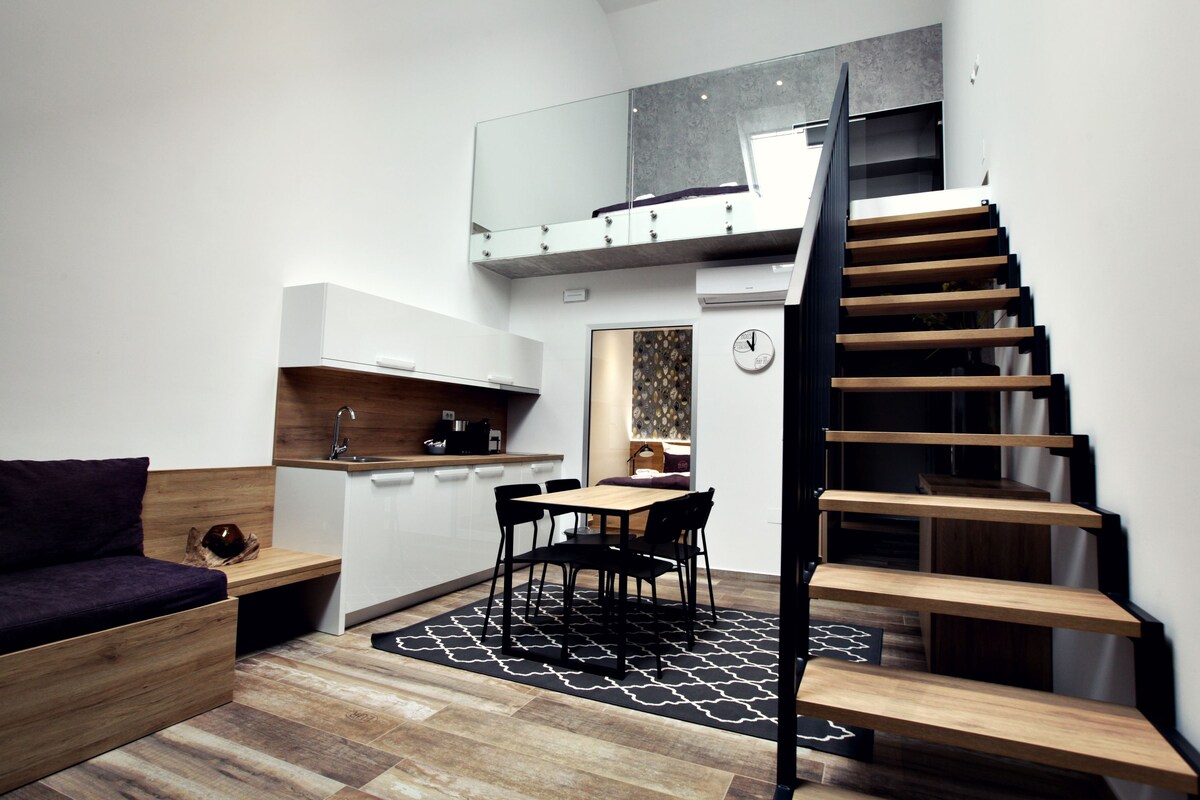 Un espace de vie compact comprenant une cuisine, un coin repas et un escalier.