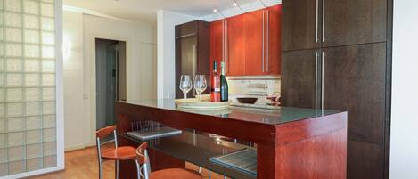 A modern kitchen with a central island, bar stools, and a wine bottle.