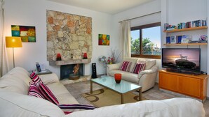 A living room with a stone wall, a fireplace, a sofa, a coffee table, and a television.