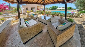 An outdoor seating area with wicker furniture and a pool in the background.